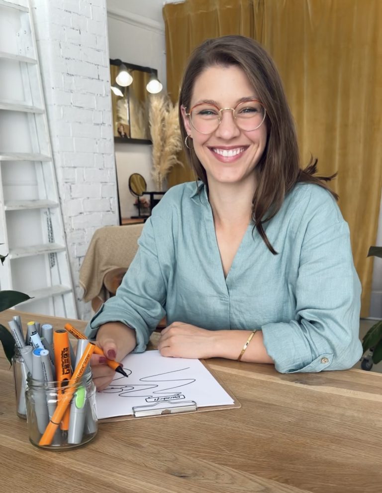 Frau visualisiert mit Papier und Stift am Tisch sitzend